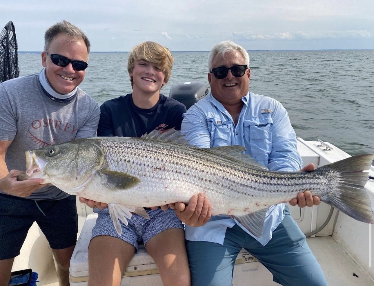 A family with a trophy striped bass aboard Chief
